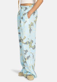 Pantalons larges à motifs bleu clair avec un design floral, taille élastique, poches latérales et texture lisse. Idéal pour un style décontracté.