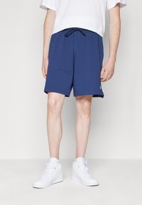 Pantaloni da ginnastica blu navy realizzati in tessuto morbido, con vita elastica dotata di cordino e tasche laterali. Design semplice, senza motivi.