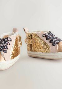 Sneakers glitterati oro per bambini con accenti rosa, lacci a stampa animale e morbida fodera bianca. Presentano una cerniera laterale e una suola testurizzata.