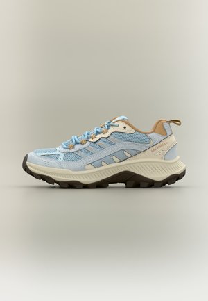 Zapato de senderismo azul claro y beige con tejido de malla, suela gruesa y suela con tacos, diseñado para uso en senderos al aire libre.