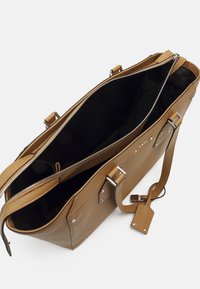 Torba na ramię z jasnobrązowej skóry z zamkiem błyskawicznym na górze, przestronnym wnętrzem, srebrnymi elementami i krótkimi uchwytami. Charakteryzuje się teksturowaną powierzchnią i bocznymi akcentami.