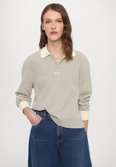 Polo a maniche lunghe a righe in crema e nero, con colletto e pattina con bottoni, abbinato a pantaloni in denim blu a vita alta.