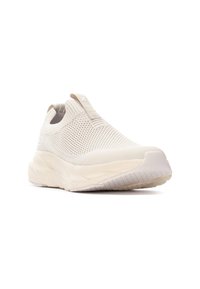 Zapatilla deportiva de slip-on en beis claro con un upper de punto texturizado y una suela acolchada. Presenta una lengüeta y un diseño minimalista.