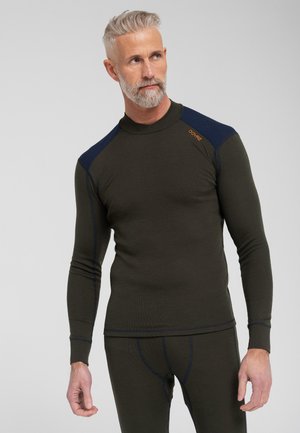 Oliven grøn termisk langærmet skjorte med en tætsiddende pasform, marineblå detaljer på skuldrene og kontrasterende syninger. Stoffet ser tekstureret ud.