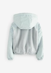 Ljusblå jacka med en plyschgrå fleecebakdel med ordet "BAKER" präglat och en huva. Elastiska ärmslut och mjuk textur är påtaglig.