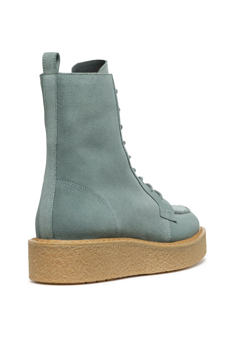 Bottines en suédine bleu clair avec une semelle plate-forme beige texturée, présentant un design à lacets et une languette à l'arrière.