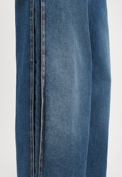 Jeans en denim bleu moyen, avec un design à jambe droite, des coutures contrastantes, et une texture lisse avec de légers détails de délavage.