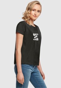 Sort bomulds T-shirt med korte ærmer viser hvid tekst, der læser "BRYT REGULERNE" i en legende skrifttype, tætsiddende design og rund hals.