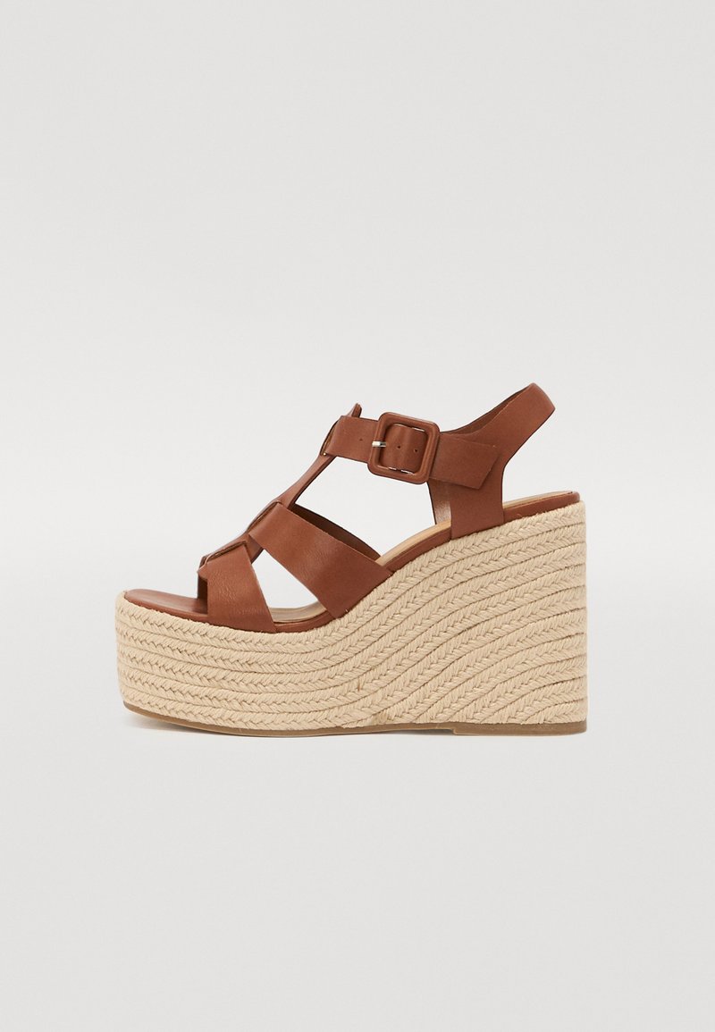 Sandali con zeppa in pelle marrone, dotati di una piattaforma in juta intrecciata, con una cinghia regolabile e un design open-toe, angolati per una migliore visibilità.