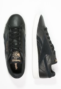 Baskets en cuir noir et suède bleu marine, dotées d'un bout rond, d'une semelle extérieure blanche, d'un laçage à l'avant et d'un logo Reebok doré sur la languette.