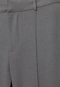 Pantalons taillés gris avec une texture lisse, présentant un devant plat, des poches latérales et des détails de couture subtils.