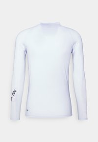Rash guard de manga larga blanca, hecho de un tejido suave y elástico, que presenta un cuello alto y un logo oscuro en la manga izquierda.