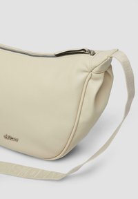 Kremowa skórzana torba o zaokrąglonym kształcie, z górnym zamkiem błyskawicznym i płaskim plecionym uchwytem. Z przodu znajdują się subtelne logo.