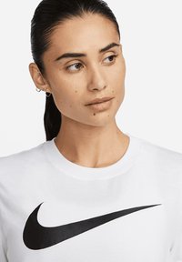 Weißes Baumwoll-T-Shirt mit prominentem schwarzem Nike-Swoosh-Logo. Rundhalsausschnitt und kurze Ärmel, glatte Textur und lässige Passform.
