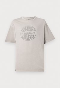 Grå t-skjorte med korte ermer laget av bomull og rund hals. Har et sirkulært grafisk design som sier "Superior Quality Garments."