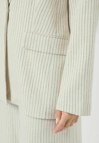 Crème-gestreepte blazer met een zak, gemaakt van gestructureerde stof en met een relaxte pasvorm. Dunne blauwe lijnen accentueren het verticale ontwerp.