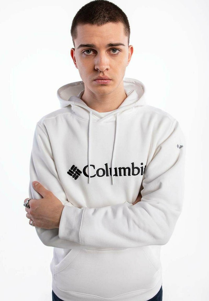 Biała bluza z kapturem z czarnym logo „Columbia” na przodzie, z kieszenią kangurzą i sznurkami przy dekolcie.