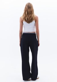 Pantaloni a gamba larga in tessuto blu scuro, con una vita elasticizzata. Il design presenta una texture morbida e una silhouette rilassata.