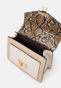 Beżowa i kremowa torebka na ramię z złotym zapięciem i wnętrzem w wzór węża. Teksturowane materiały w strukturalnym, prostokątnym kształcie.