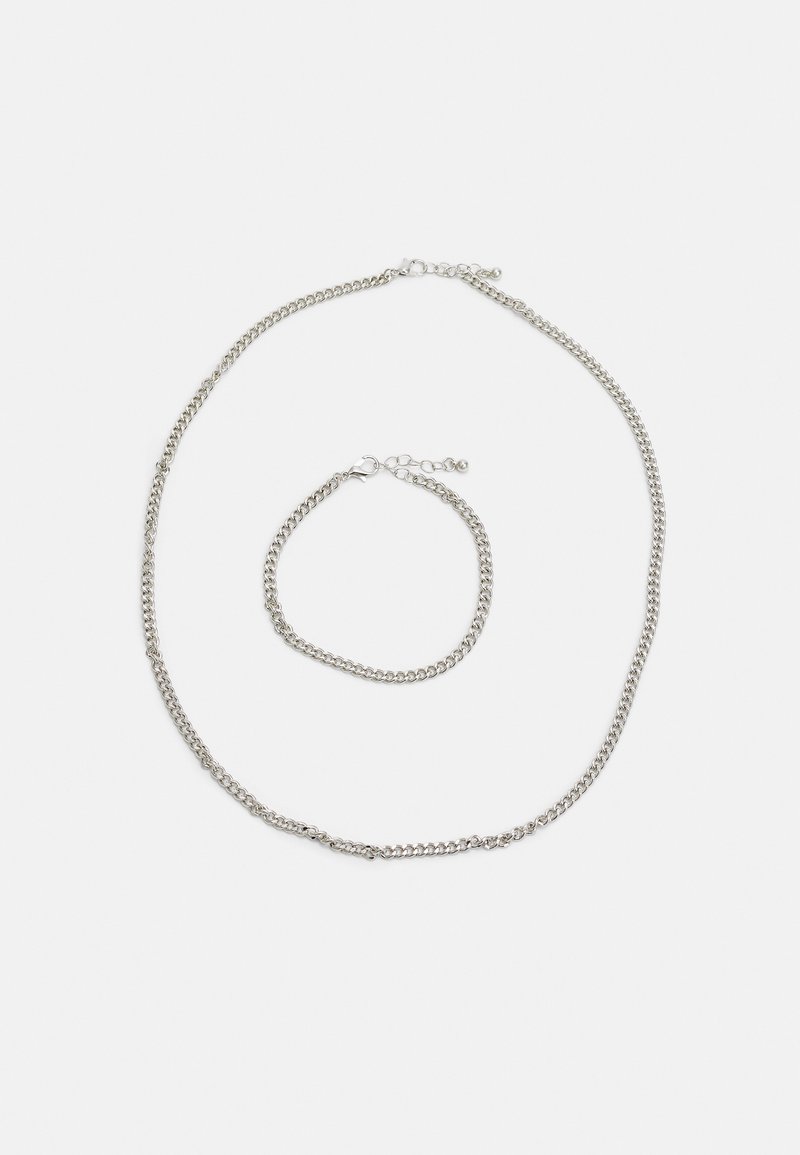 Conjunto de colar e pulseira em prata; apresenta elos entrelaçados com uma textura suave. Ambos têm um fecho em lagosta para ajuste.