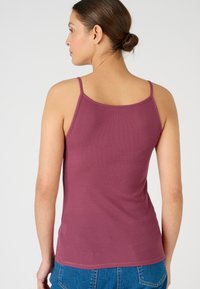 Ribbed maroon tank top with thin straps, featuring a fitted design and a smooth texture, paired with blue denim.