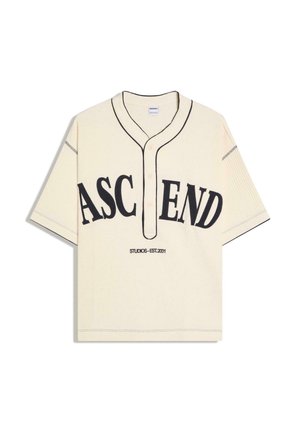 Tricou crem stil baseball cu mâneci scurte, margini negre, nasturi în față și text mare negru "ASCEND" cu "STUDIOS - EST. 2001" dedesubt.