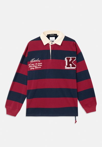Poloshirt met lange mouwen heeft rode en marineblauwe horizontale strepen, een beige kraag, geborduurd logo en een decoratieve letter "K" patch.