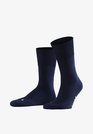 Para granatowych skarpetek do połowy łydki z żebrowanymi mankietami i małym żółtym napisem w pobliżu palców oraz po bokach.