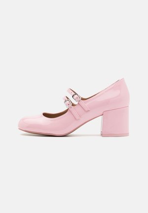Des chaussures Mary Jane en cuir verni rose avec un bout rond, des sangles à double boucle et un talon épais. Texture lisse et finition brillante.