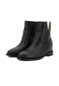Schwarze Leder-Stiefeletten mit glatter Textur, die ein minimalistisches Design aufweisen und ein markantes V-förmiges goldfarbenes Akzent auf der Seite haben.