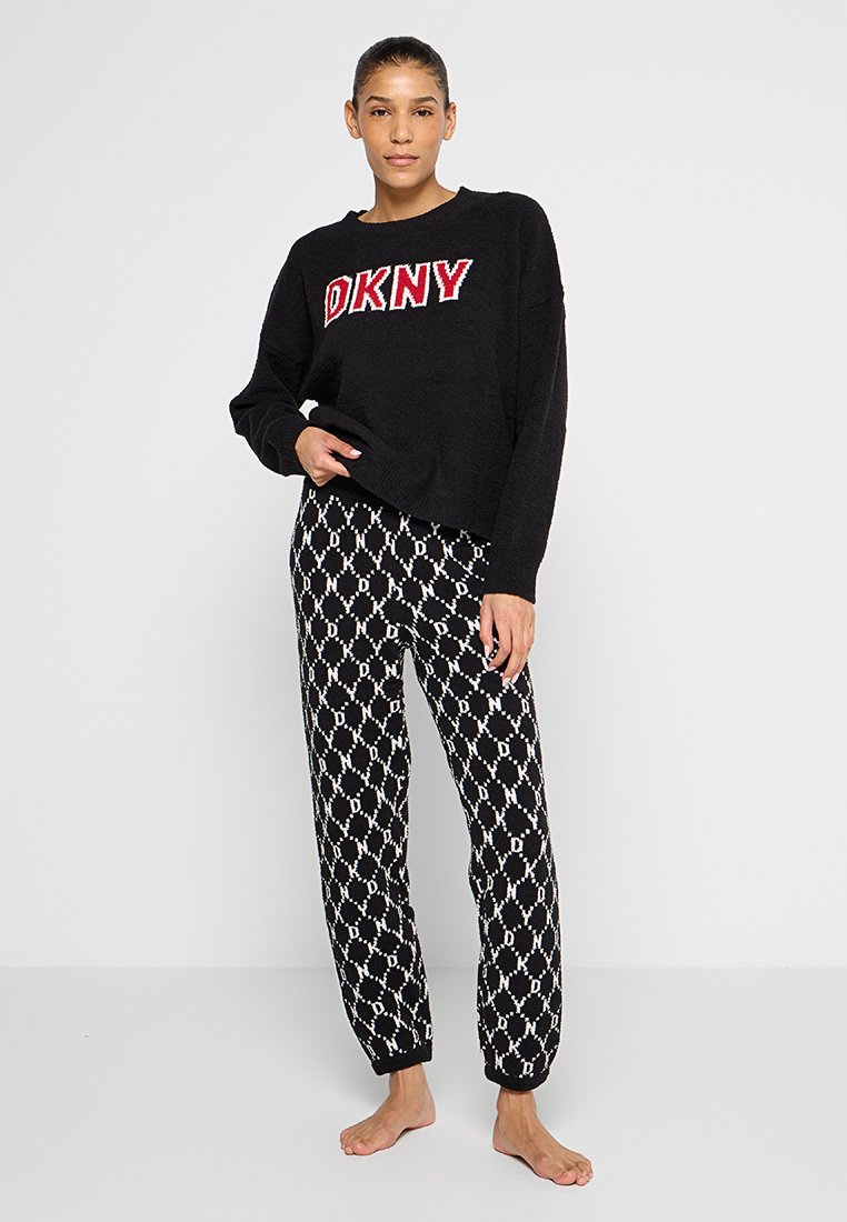 Schwarzer Strickpullover mit rotem "DKNY"-Logo. Schwarze und weiße Jogginghose mit diamantförmigem Muster und entspanntem Schnitt.