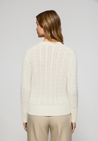 Streifenpullover in Creme mit einem strukturierten Muster, gerippten Bündchen und Saum sowie Rundhalsausschnitt. Die Rückansicht zeigt das filigrane Design.