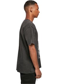 Mørk grå oversized t-shirt i bomuld med korte ærmer, rund halsudskæring og en falmet finish. Har grafisk tekst på forsiden.