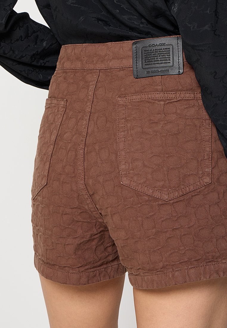 Braune Shorts mit Struktur und geometrischem Muster, mit hoher Taille, Gesäßtaschen und einem markierten Lederpatch am Bund.