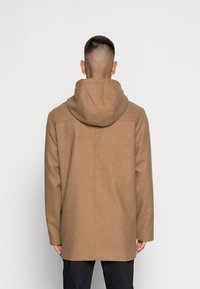 Bruine wollen mix jas met een capuchon, met een rechte snit en een achternaaddetails. De stof heeft een zachte, gestructureerde uitstraling.