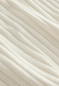 Bijela teksturirana tkanina s suptilnim horizontalnim trakama, mekana na dodir, s pahuljastim, fluffy izgledom. Idealna za razne tekstilne primjene.