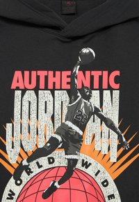 Μαύρο φούτερ με κουκούλα με εικόνα ενός καλαθοσφαιριστή στον αέρα, που φοράει φανέλα με τον αριθμό 23, πάνω σε φόντο με υφή ραγισμάτων.