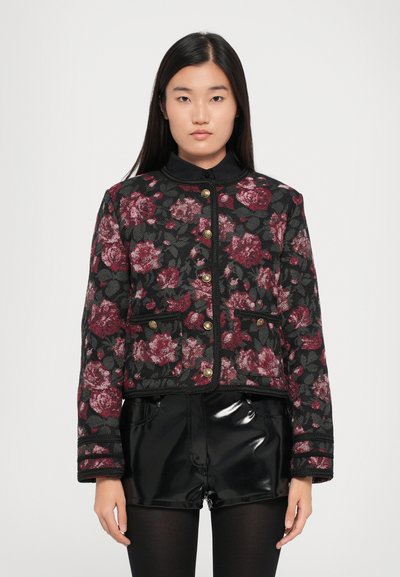 Giacca nera floreale con motivi di rose rosse e rosa, chiusure con bottoni dorati, tessuto testurizzato e bordo nero a contrasto. Design corto e strutturato.