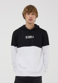 Felpa con cappuccio color block in bianco e nero, con tasca a marsupio, cappuccio regolabile e logo stampato "ESSENTIAL" sul petto. Tessuto morbido.