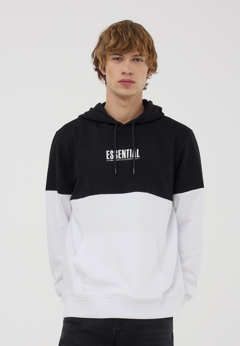 Felpa con cappuccio color block in bianco e nero, con tasca a marsupio, cappuccio regolabile e logo stampato "ESSENTIAL" sul petto. Tessuto morbido.