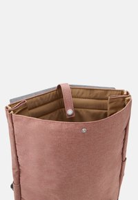 Mochila de tela rosa con parte superior gris, que presenta un cierre a presión y un interior forrado. Dos bolsillos interiores y una textura suave.
