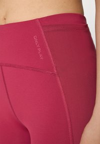 Magenta athletic leggings with a smooth texture, featuring a stitched seam and the text "ONLY PLAY" in a contrasting color.