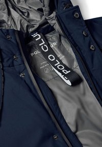 Marinblå jacka med grå inredning; har en svart logoband och tryckknappar. Mjuk textur med huva och dragkedjeöppning.