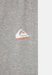 Grå hettegenser laget av bomullsblanding; har Quiksilver-logo i hvitt og oransje; myk tekstur med en avslappet passform og uten distinkte mønstre.