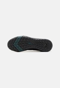 Shoe sole with wave-like treads. Black rubber with a dark teal accent band. Textured grip pattern for traction.