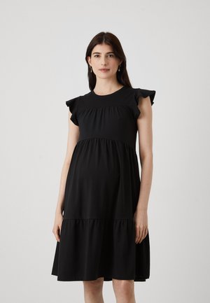 Robe de maternité noire avec des manches courtes à volants, un buste froncé et une jupe à étages. Tissu lisse avec une coupe décontractée et une longueur au genou.