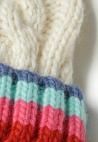Strickmütze mit einem einfarbigen cremefarbenen Oberteil und einem mehrfarbigen gerippten Bund in Rottönen, Pink, Mint und Blau mit einer strukturierten Oberfläche.