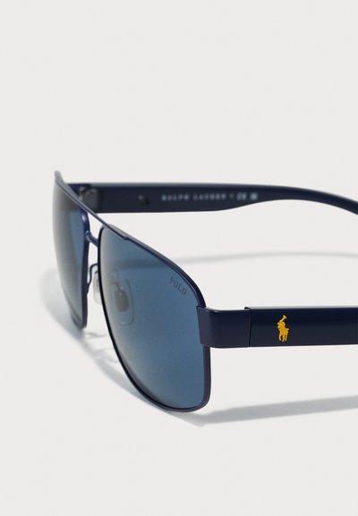 Ochelari de soare bleu marin cu lentile mari, tonifiate. Prezintă un logo Polo auriu pe cadru și un design elegant, unghiular, cu brațe drepte.