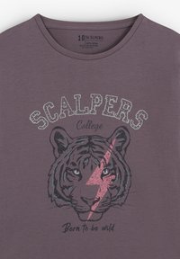 Camiseta de algodón morada con un gráfico de un tigre con ojos azules y un rayo rosa. El texto "SCALPERS College" está en la parte superior en color plata.