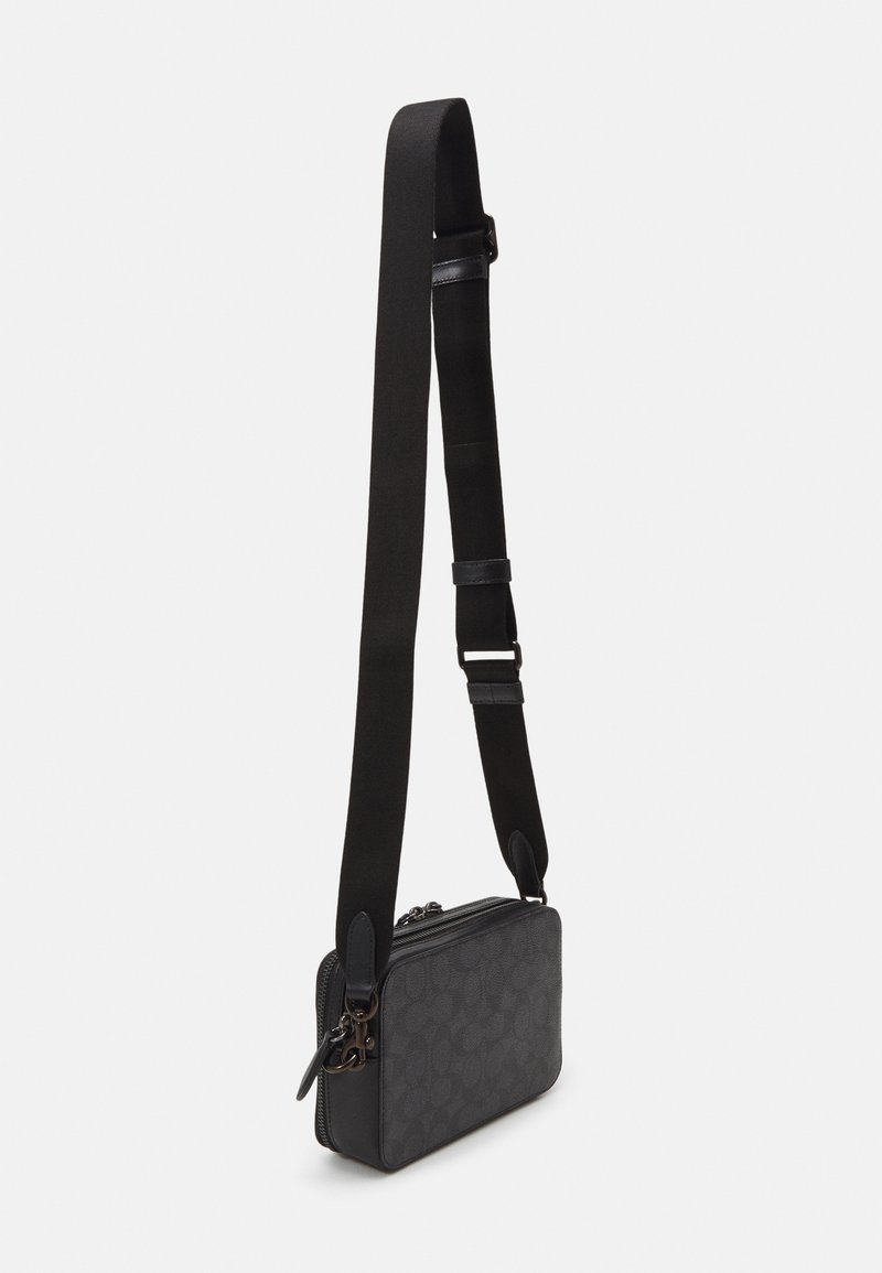 Bolso de hombro negro con exterior texturizado, cierre de cremallera y correa ajustable. Presenta patrones sutiles y acentos de cuero.